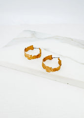 Envy Gold hoop earrings on a white fabric background