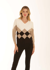 A woman modeling a long-sleeve V-neck sweater with a color-blocked argyle pattern in cream, beige, black, and brown, paired with black pants against a plain white background.
