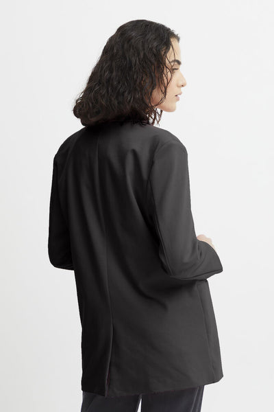 A model shown from a side-back angle wearing an oversized black long-sleeve blazer against a plain white studio background.