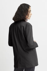 A model shown from a side-back angle wearing an oversized black long-sleeve blazer against a plain white studio background.
