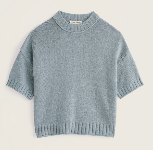 Seasalt light blue short sleeve knit sweater with a crew neck and ribbed trim, laid flat against a warm off white background.