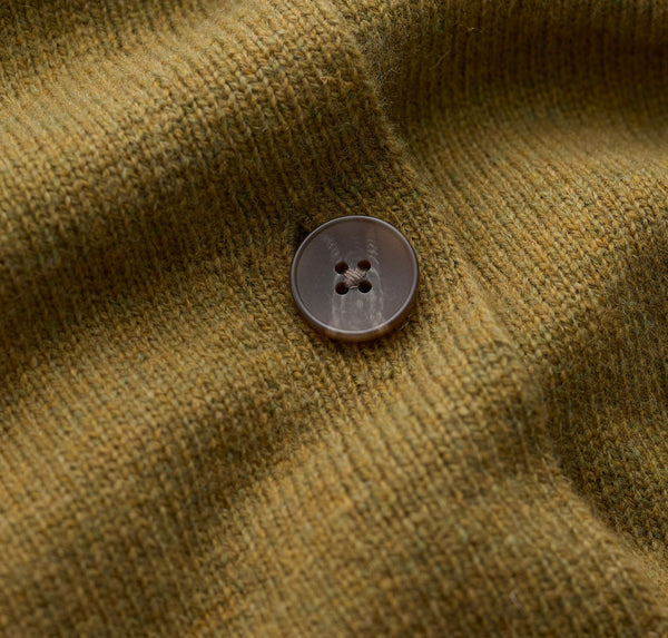 Close up of Seasalt ribbed knit fabric in a muted olive-brown tone with a single round button on the front.