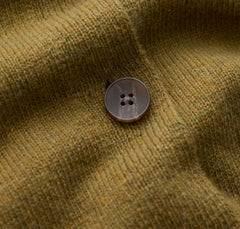 Close up of Seasalt ribbed knit fabric in a muted olive-brown tone with a single round button on the front.