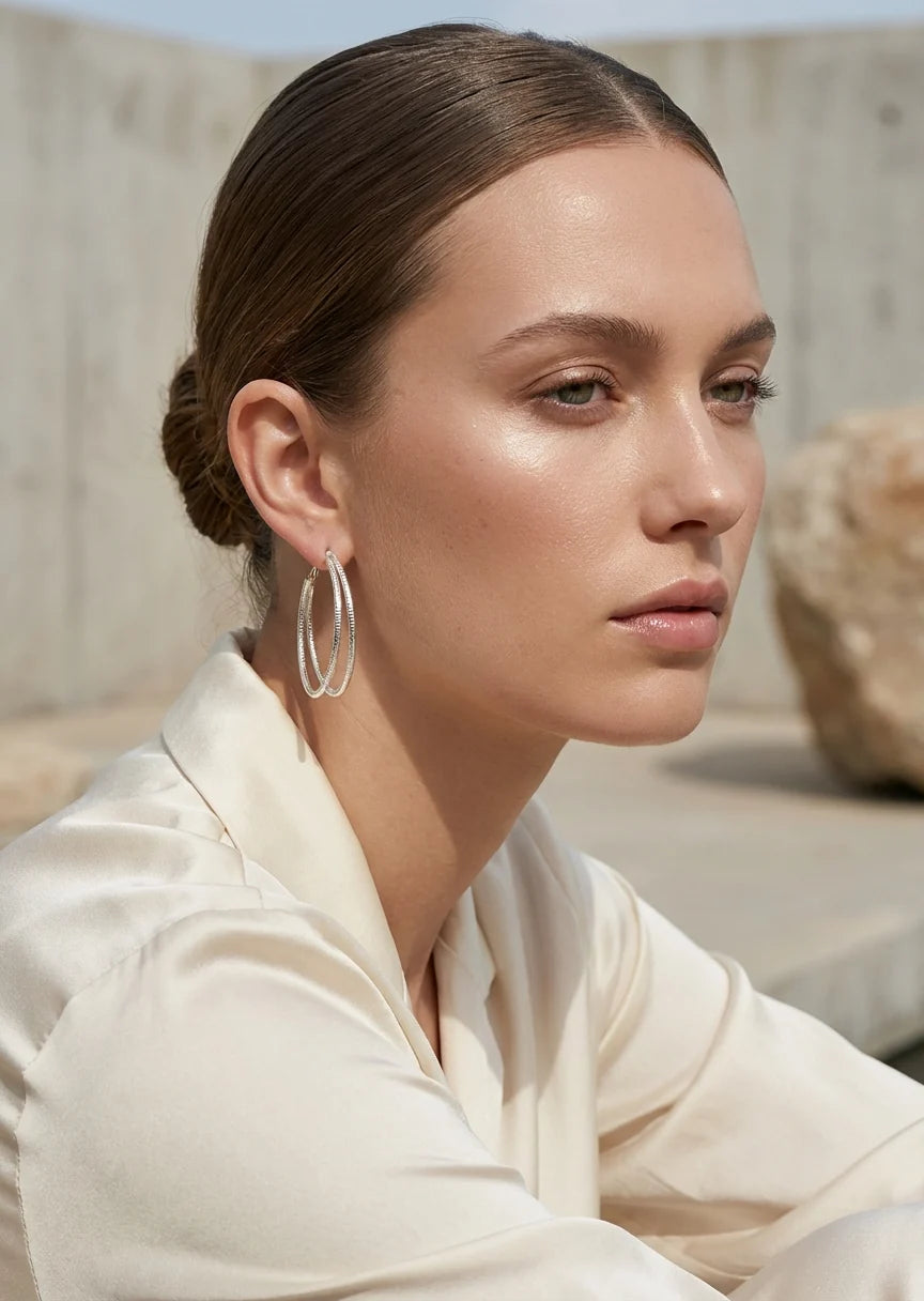 Woman wearing Envy gold  hoop earrings with a neutral background