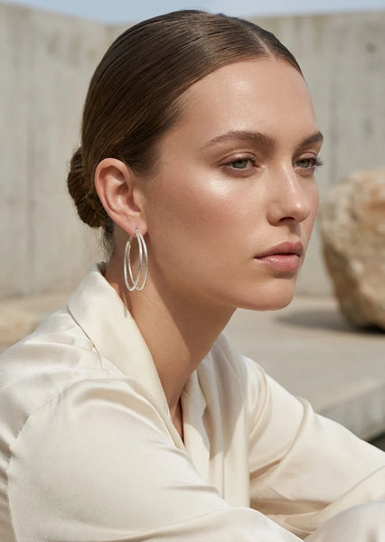 Woman wearing Envy gold  hoop earrings with a neutral background