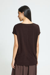 A woman shown from the back wearing a dark brown short-sleeve top and matching brown bottoms against a light gray studio background.