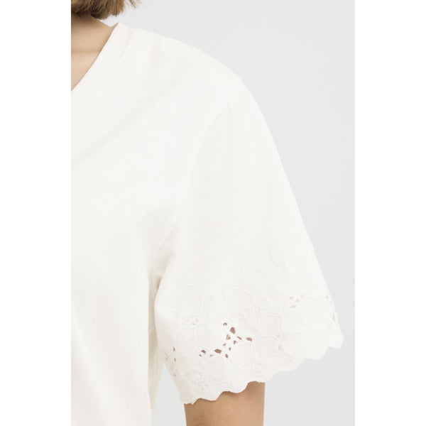 White lace top with scalloped hem on a white background