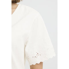 White lace top with scalloped hem on a white background