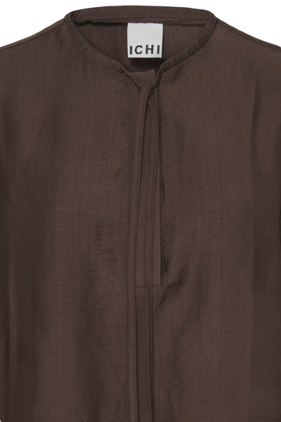 Close-up of a dark brown textured fabric garment with a stand collar and a white neck label reading 'ICHI'.