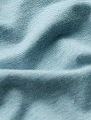 A close-up of light blue knit fabric with soft folds and a fine ribbed texture.