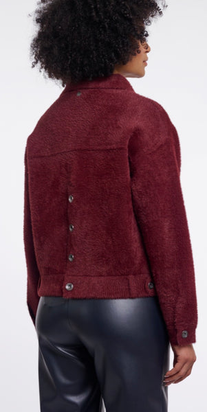 A person shown from the back wearing a Rino & Pellet burgundy cropped jacket with buttons and black leather pants against a plain light background.