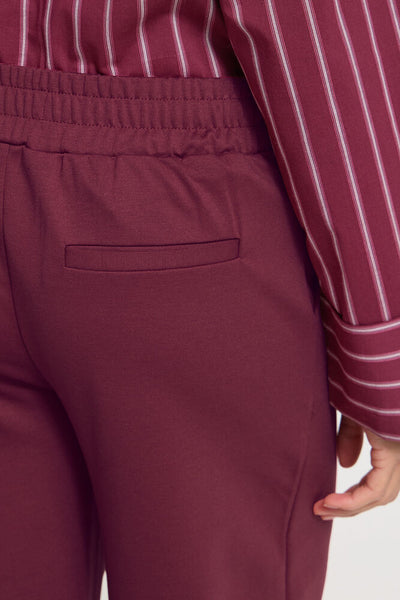 Maroon pants with a striped shirt on a white background
