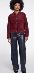 A model wearing a Rino & Pelle burgundy cropped jacket and shiny black wide-leg trousers, standing against a light grey studio background. 