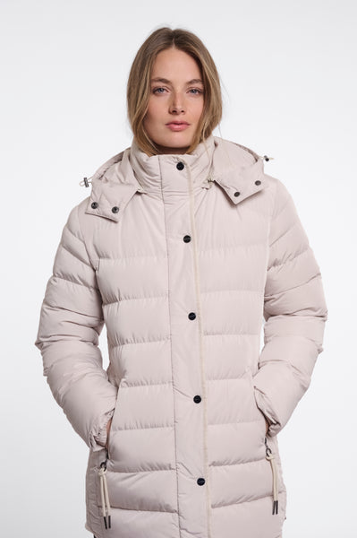 A woman wearing a Rino & Pelle light beige padded coat with a high collar and black snap buttons, photographed against a plain white studio background.