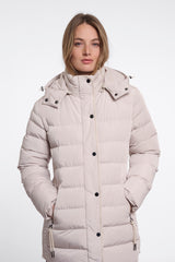A woman wearing a Rino & Pelle light beige padded coat with a high collar and black snap buttons, photographed against a plain white studio background.