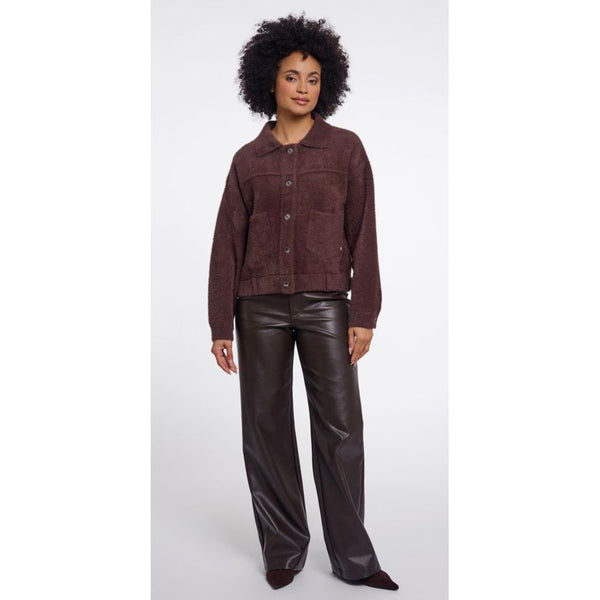 A model wearing a Rino & Pellet dark brown textured button up jacket and dark brown wide-leg faux-leather pants, standing against a light grey studio background.