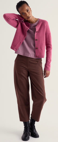 A model wearing Seasalt dusty pink cropped cardigan over a mauve top, paired with brown cropped trousers and black lace-up ankle boots, against a light gray studio background.