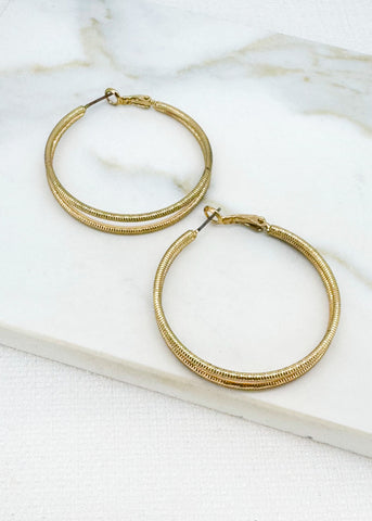 Envy Jewellery large Gold hoop earrings on a marble surface.