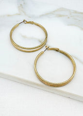 Envy Jewellery large Gold hoop earrings on a marble surface.