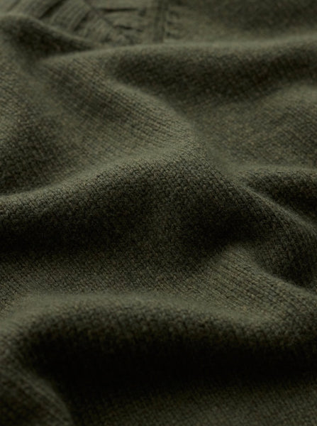 Close-up of a dark olive green knit fabric with soft folds and a ribbed texture.