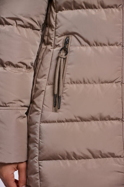 Close-up of a padded coat in a taupe-beige colour showing horizontal stitching, a vertical zippered pocket with a matching zipper pull, and a hand at the bottom left.