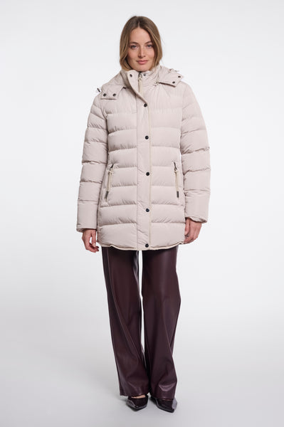 A woman modelling a Rino & Pelle light beige padded coat with a high collar and front buttons, paired with dark brown wide-leg trousers, against a plain white studio background.
