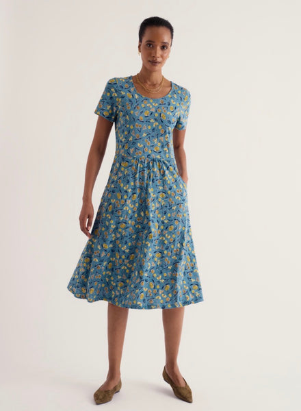 A woman modelling Seasalt short sleeve midi dress with a blue and yellow floral print, standing against a plain light background.