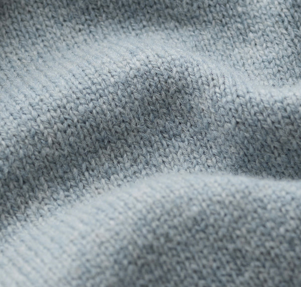 Close up of a light blue  knit fabric texture with soft folds and visible knit stitches.
