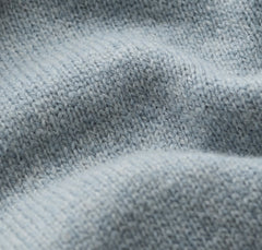 Close up of a light blue  knit fabric texture with soft folds and visible knit stitches.