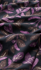 A close-up of draped fabric with a dark navy background and a repeating floral pattern in purple and brown with light cream accents.