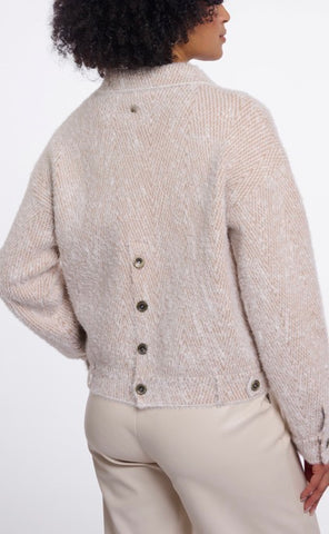Close-up of a textured cream-colored knit fabric with two dark metal buttons.