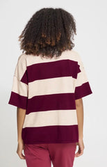A person shown from the back wearing an Ichi oversized short-sleeve striped top with wide cream and burgundy horizontal bands, paired with burgundy pants, against a plain light grey  studio background.