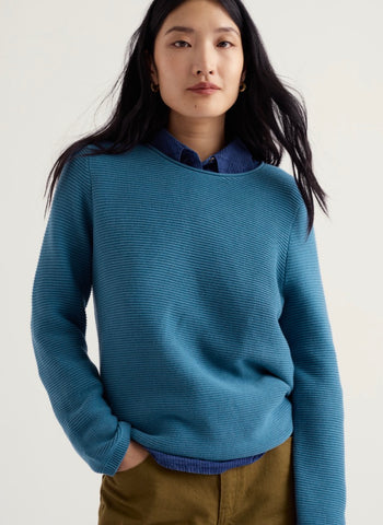 Close up of a blue ribbed knit fabric texture with horizontal rows and soft folds.