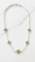 Envy Jewellery silver-toned chain necklace featuring five textured starburst or snowflake charms, displayed on a white marble surface.