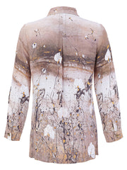 A women's long-sleeve button-down Dolcezza shirt shown from the back, featuring an abstract painterly print in shades of beige, brown, white, and black with subtle gold accents.