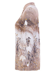 A side-profile view of a women's Dolcezza long-sleeve collared shirt featuring an abstract paint-splatter print in beige, brown, white, and black with small yellow accents, set against a plain white background.