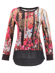 A long-sleeve Dolcezza top featuring a vibrant pink, red, and blue floral print on one side, transitioning into a black and brown vertical tree trunk pattern on the other, finished with a solid black ruffled hem and cuffs.