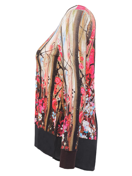A long-sleeve sheer top with a vibrant abstract floral and brushstroke print in pink, red, gold, and black, featuring solid black cuffs and hem.