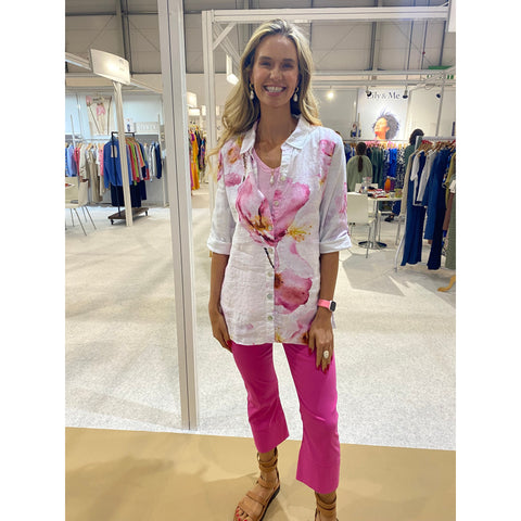 Woman wearing a floral blouse and pink pants in a clothing store.
