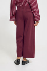Person wearing a maroon striped shirt and wide-leg pants on a white background