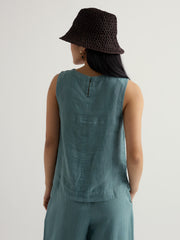 Wearing a teal sleeveless top and matching pants with a bucket hat on a light grey background.