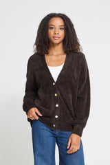 Model wearing an Ichi chocolate brown button up cardigan with a white top and blue jeans in a studio background. 