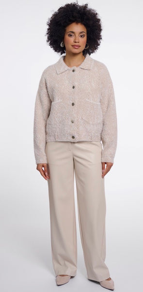 A woman modelling Rino & Pelle  light beige textured button-up cardigan with a collar and front pockets, paired with beige wide-leg trousers, against a plain white studio background.