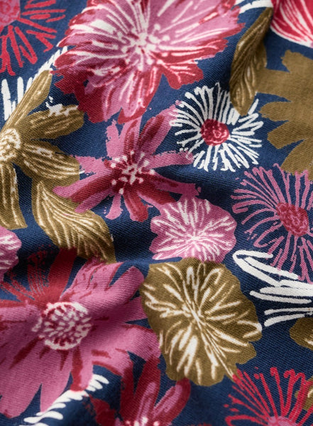 A close up of a floral fabric pattern featuring large stylized flowers in pink, red, and metallic gold on a dark navy blue background.