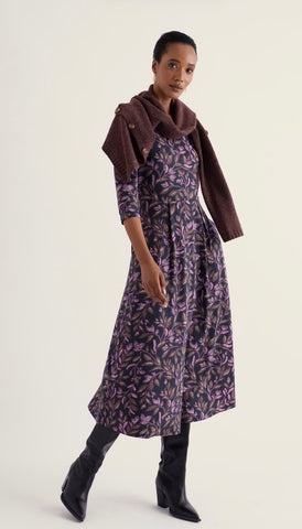 A close-up of draped fabric with a dark navy background and a repeating floral pattern in purple and brown with light cream accents.