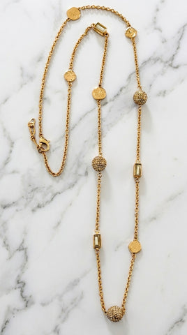 Envy Jewellery gold-toned beaded necklace with textured disc, spherical, and rectangular beads, displayed on a white marble background.