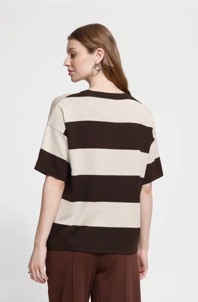Back profile of woman wearing an Ichi brown and cream striped Ichi Top with brown trousers against a light grey background