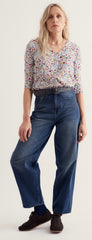 A woman modelling Seasalt floral print blouse and wide leg blue jeans against a plain light background.