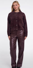 A woman modeling Rino & Pelle dark plum brown button up jacket with matching faux-leather pants against a plain white studio background.