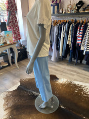 Mannequin wearing a light blue trousers with a blurred store background